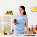 Pregnant woman holding a glass of cranberry juice in kitchen | side effects of cranberry juice during pregnancy